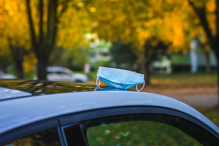 Forgotten face mask on car roof during pandemic of coronavirus. New normal during COVID-19 epidemicの写真素材
