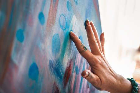 Painting on canvas using just hands and fingers. Abstract art paintings. Woman artist working in her studioの写真素材