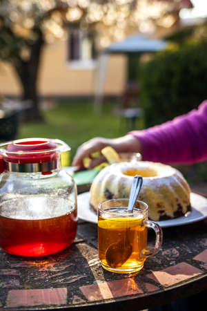 Tea cup and teapot with bundt cake on table. Serving dessert and hot drink in spring gardenの写真素材