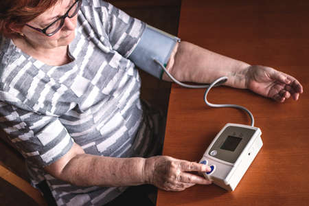 Senior woman measuring blood pressure at home. Everyday life for hypertension patientの写真素材