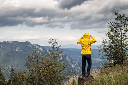 Strong wind in the mountains. Woman wearing sports clothing during hiking in wilderness. The weather in the mountains is changing rapidlyの写真素材