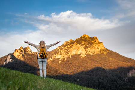 Woman enjoying hiking in mountains. Travel and active lifestyle concept. Carefree female tourist is feeling fresh air in natureの写真素材
