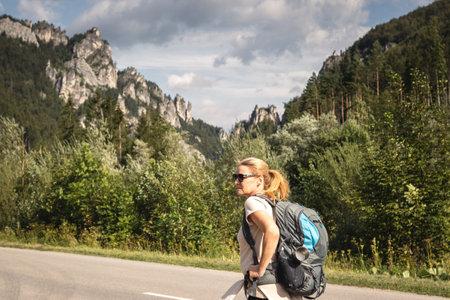 Traveler hiking on road at mountains in natural park Mala Fatra, Slovakia. Travel and active lifestyle concept. Woman with backpack during summer vacationの写真素材