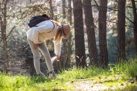 Woman spraying insect repellent against tick at her legs. Protection against mosquito bite during hike in forestの写真素材