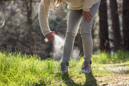 Woman spraying insect repellent against tick at her legs. Protection against mosquito bite during hike in forestの写真素材