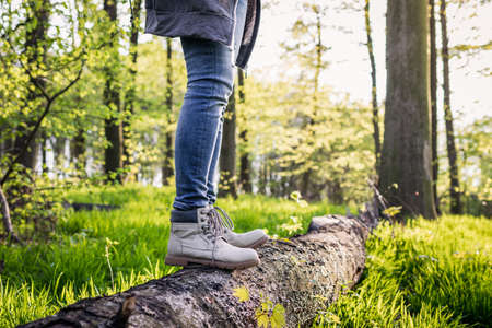 Hiking in the forest. Woman with leather hiking boots standing on tree trunk at woodland. Active lifestyle in natureの写真素材