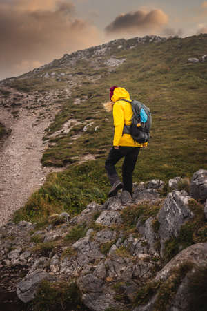 Mountain climbing. Woman with backpack and sport clothing hiking outdoors in natural park Mala...