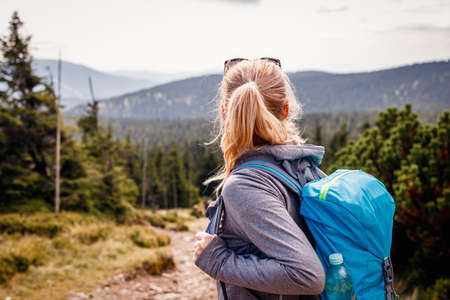 Mountain hike. Tourist enjoying scenic view in nature. Woman with backpack looking at mountain range. Travel active lifestyle and adventure conceptの写真素材