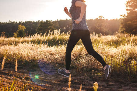 Woman running in nature during summer sunset. Female runner jogging outdoors. Sport and active lifestyleの写真素材