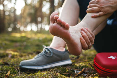 Sprain ankle during hiking in nature. Woman feeling pain after accident injury outdoorsの写真素材