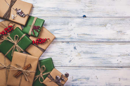 Wrapped Christmas presents with decoration on white wooden table. Flat lay of gift boxes in green...