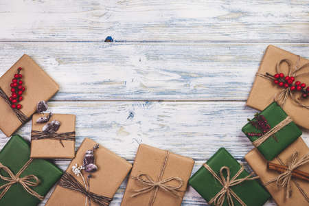 Wrapped Christmas presents with decoration on white wooden table. Flat lay of gift boxes in green and brown kraft wrapping paperの写真素材