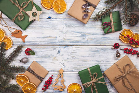 Wrapped Christmas presents and decoration on white wooden table. Flat lay of gift boxes in green and brown kraft wrapping paperの写真素材