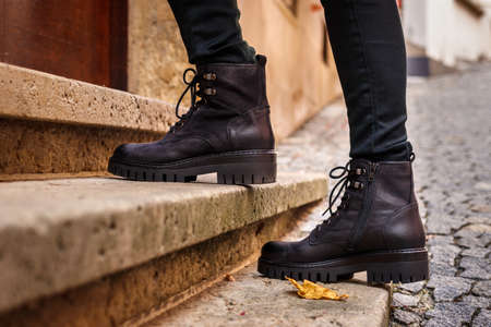 Trendy black leather boots. Close-up stylish shoes. Female legs walking on staircase on streetの写真素材
