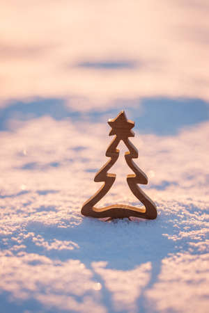 Wooden Christmas tree decoration in snow during sunset. Winter greeting card backgroundの写真素材