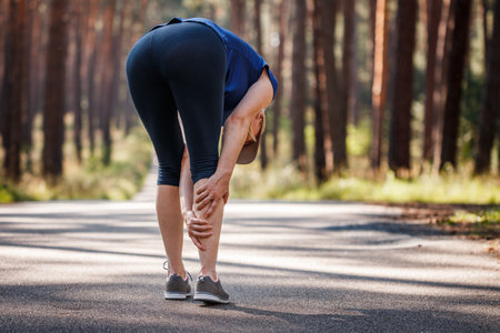 Calf muscle cramp. Woman feeling pain of her legs during jogging. Underestimating the warm-up exercise before runningの写真素材