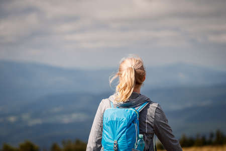 Rear view of woman with backpack hiking in mountains. Adventure in natureの写真素材