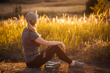 Female runner resting after jogging outdoors. Woman taking a break after exercise. Fitness active lifestyleの写真素材