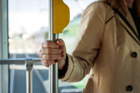 Woman holding pole in city bus. Hygiene risk when holding the handle in commuter. Traveling by public transportationの写真素材