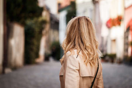 Stylish woman wearing trench coat and walking on city street. Fashionable trendy styleの写真素材