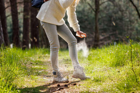 Woman spraying insect repellent against tick at her legs. Protection against mosquito bite during hike in woodlandの写真素材