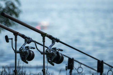 Fishing rod at lake or riverbank. Catching fish in nature. Close-up fishing reel