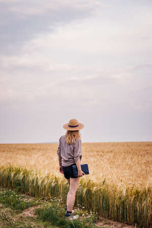 Farmer examining and looking at agricultural field before harvest. Woman with straw hat and digital tablet standing in barley fieldの写真素材