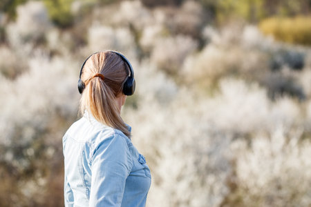 Woman with headphones listening music outdoors. Female person relaxing and enjoying spring natureの写真素材