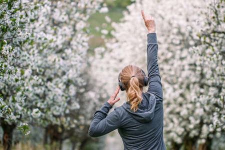 Happy woman with headphones listening music and dancing outdoors in spring nature. Enjoyment and happiness of carefree lifeの写真素材
