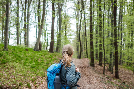 Hiking in the forest. Woman with backpack trekking on footpath in woodland