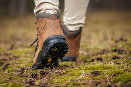 Tourist with hiking boots walking on footpath in forest. Trekking trail in woodland. Waterproof leather ankle bootの写真素材