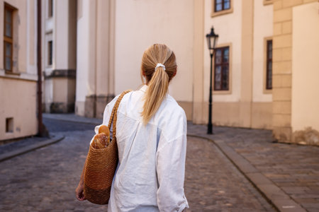 Caucasian woman with straw bag walks on street in old town. City life in Europeの写真素材