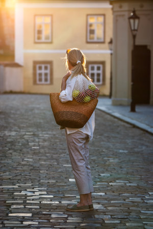 Woman with reusable bag standing on city street. Sustainable lifestyle conceptの写真素材
