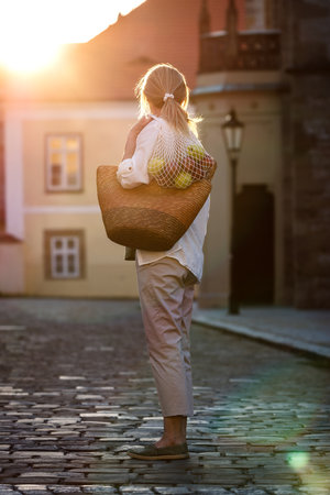 Blond hair woman with reusable bag standing on city street after shopping food. Sustainable lifestyle conceptの写真素材