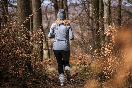 Fitness training and jogging in fall forest. Woman running outdoors. Sports activity in natureの写真素材