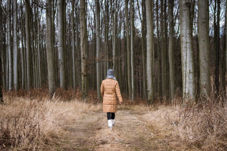 Woman wearing warm clothing and walking in autumn forest. Active lifestyle outdoorsの写真素材
