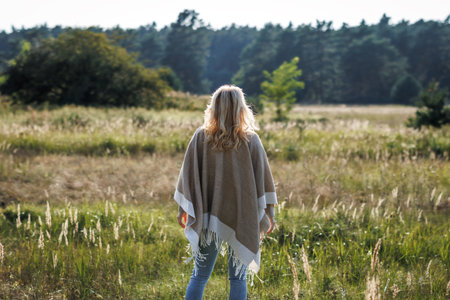 Boho woman with poncho standing outdoors. Enjoyment of spending time in nature