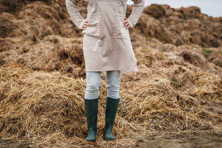 Farmer with apron and rubber boots standing next to manure pile with animal dung. Organic farmingの写真素材