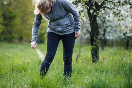 Woman applying insect repellent against mosquito and tick on her leg before jogging in spring natureの写真素材