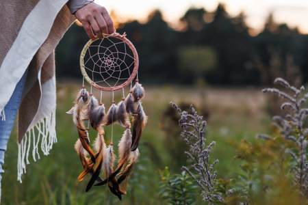 Woman with poncho holding dreamcatcher outdoors. Spirituality and harmony between people and natureの写真素材