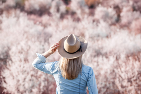 Woman with hat is feeling happiness in nature at spring season. Female person enjoying springtime outdoorsの写真素材