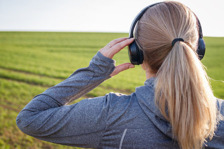 Woman exercising outdoors while listening to music on her wireless headphones. Workout in natureの写真素材