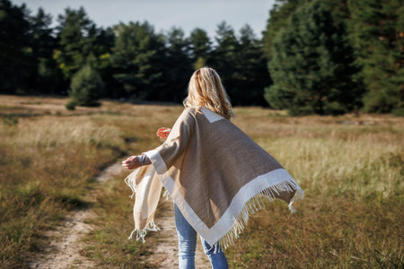 Woman with poncho running on footpath in nature. Female person in motionの写真素材