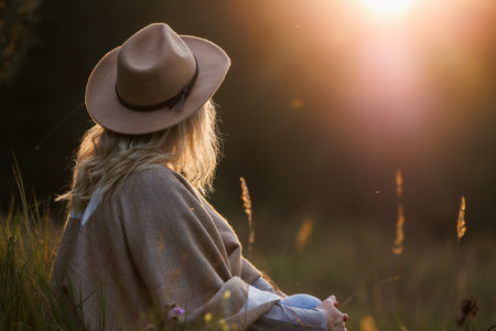 Woman enjoying harmony and life balance with nature during sunset. Relaxation outdoors for good mental health and improve mindfulnessの写真素材