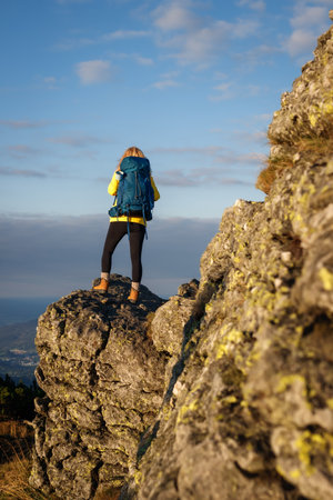 Woman tourist with backpack trekking in mountains. Hiker successfully climbed mountain summit. Hiking is adventureの写真素材