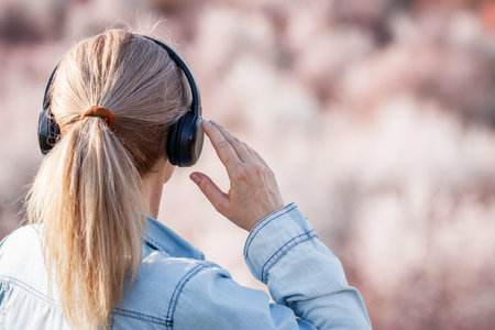 Woman with headphones listening music outdoors. Female person relaxing and enjoying spring natureの写真素材