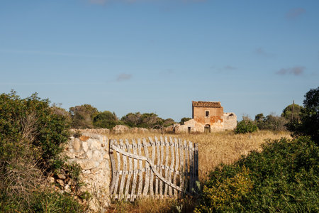 Abandoned farm building in the fields with old wooden gate and stone wall in Mallorca.の写真素材