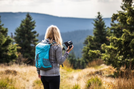 Woman photographer with backpack and camera hiking in mountains. Adventure in natureの写真素材