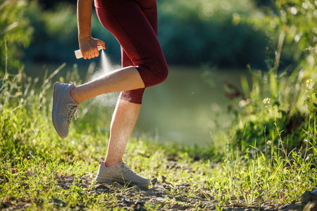 Woman applying insect repellent against mosquito and tick on her leg before jogging in natureの写真素材