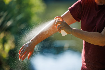 Woman applying insect repellent on her arm outdoors. Skin protection against ticks and mosquito bitesの写真素材